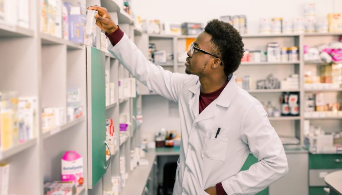 A man in a lab coat works in a pharmacy.