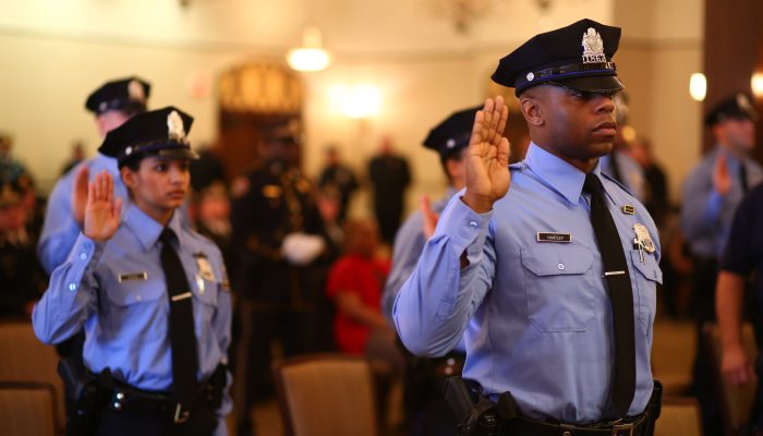 Group of police officers with right hands raised as they take an oath.