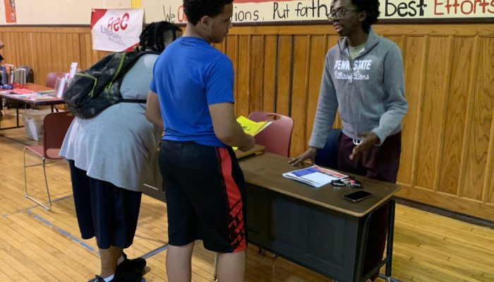 Quinetta Bowden from SquashSmarts speaks with students at an activity fair in a school gym