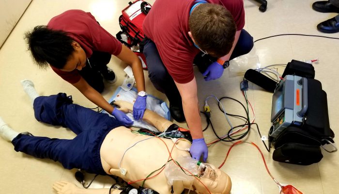 man and woman kneel over intubated dummy lying on floor