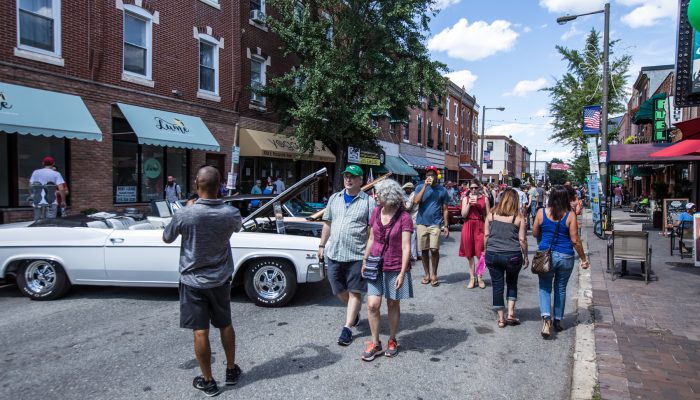 People walk along East Passyunk Avenue during the annual car show