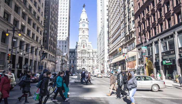 A group of people crossing Broad Street in front of Philadelphia City Hall.