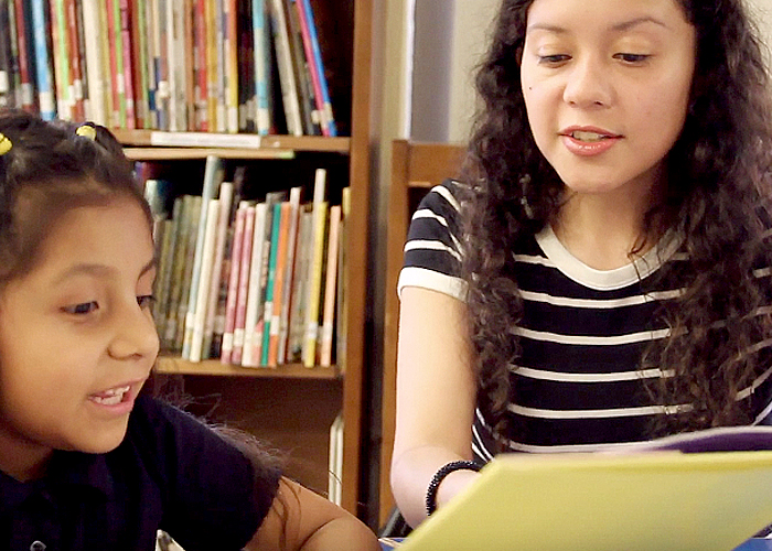 Reading coach volunteer reading to a young girl