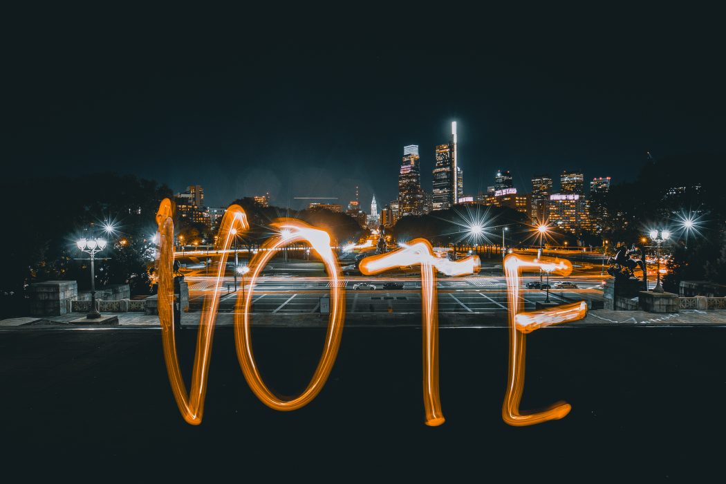 a light painting of the word vote with the philadelphia skyline in the background