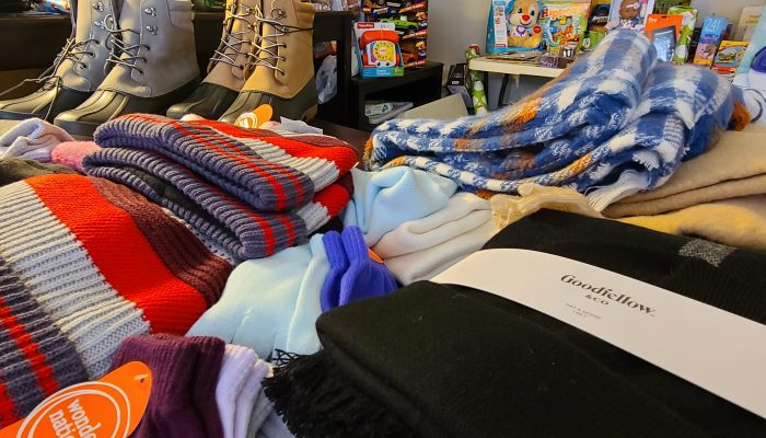 Toys, winter scarfs and hats and boots sit on a table. The items were collected in annual holiday toy and clothing drive.