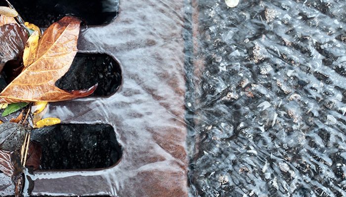 Water pours into a sewer grate.