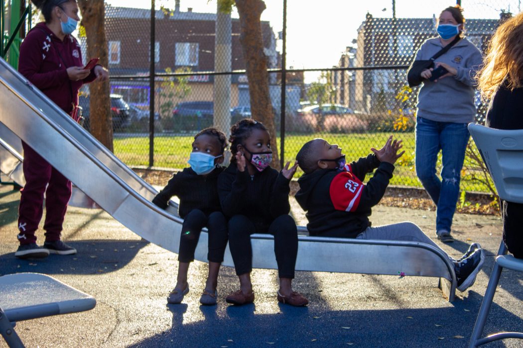 Three children sitting on a slide.
