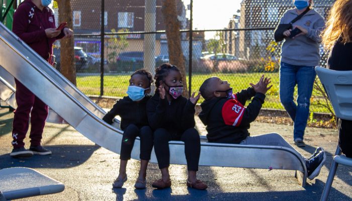 Three children sitting on a slide.
