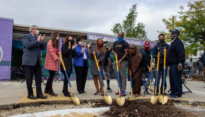 Multiple people gathered with shovels to break ground on a construction project at Miles Mack Playground.