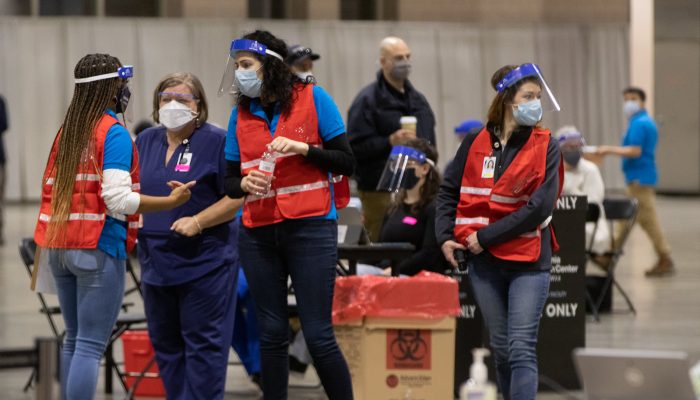 Nurses and other medical personnel wear plastic face shields as well as heavy duty surgical masks as they talk at a Philadelphia COVID-19 vaccine clinic at the Pennsylvania Convention Center.