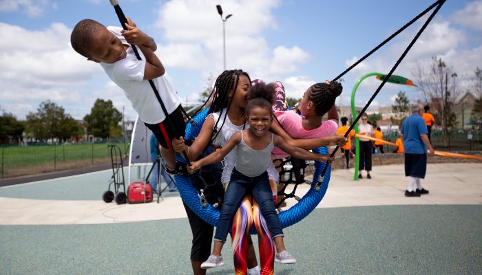 Four children play together on a playground swing set.