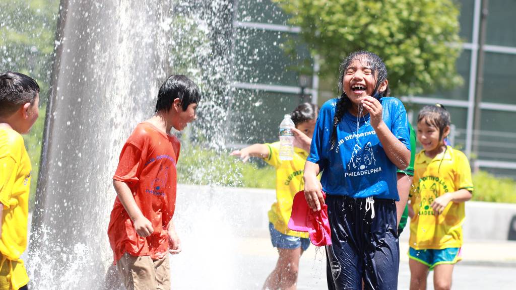 A girl smiles while playing in an outdoor water fountain
