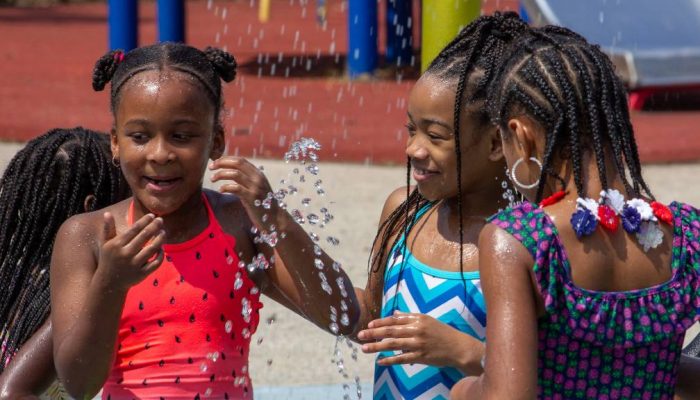 Three girls play in a public sprinkler in Philadelphia