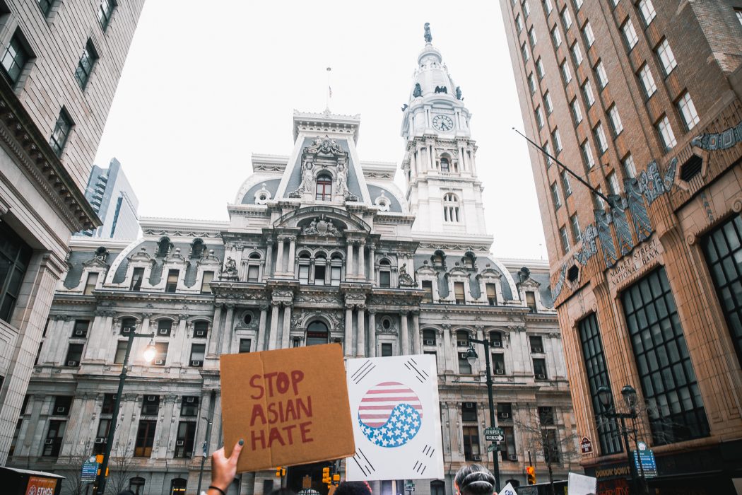 City Hall with hand holding sign that reads," stop asian hate."