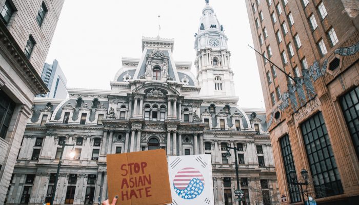 City Hall with hand holding sign that reads," stop asian hate."