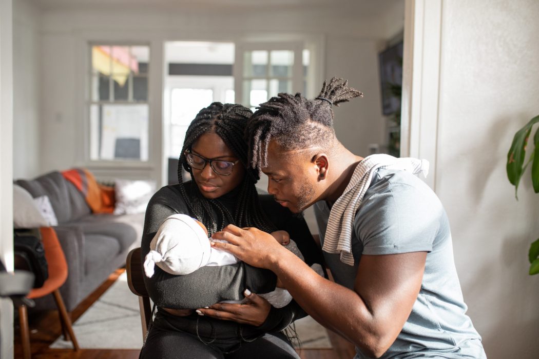 A man and woman look at a baby