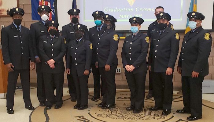 Eleven people in dress uniforms with caps and face masks