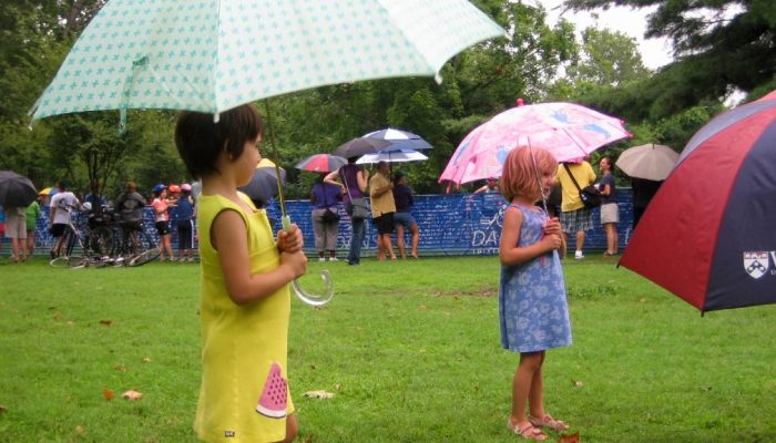 Dos niñas utilizan paraguas para protegerse de la lluvia en evento al aire libre