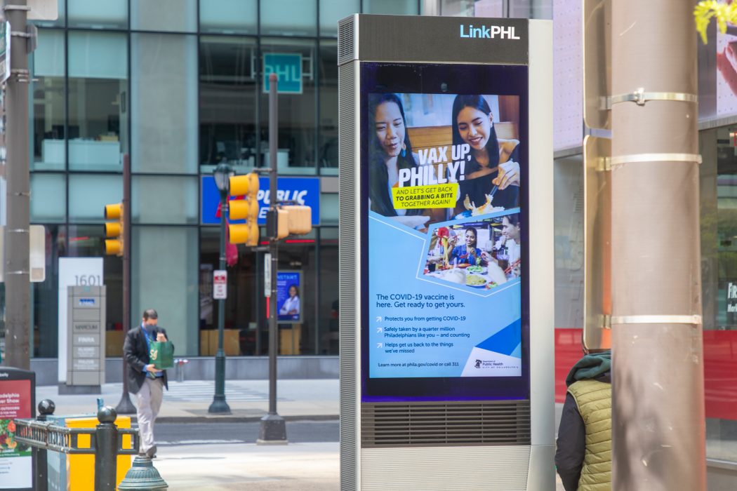 An electronic ad on a center city sidewalk that says "VaxUpPhilly"