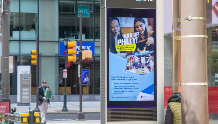 An electronic ad on a center city sidewalk that says "VaxUpPhilly"