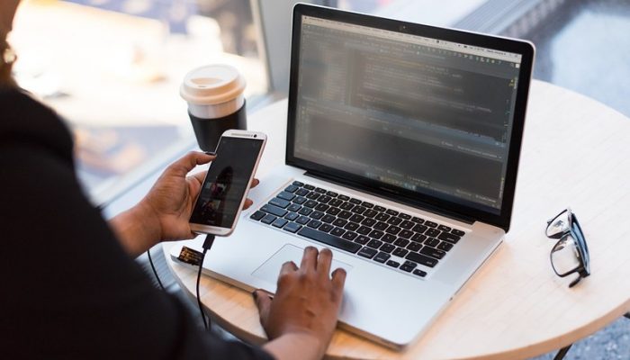 A person uses their mobile phone and their laptop at the same time