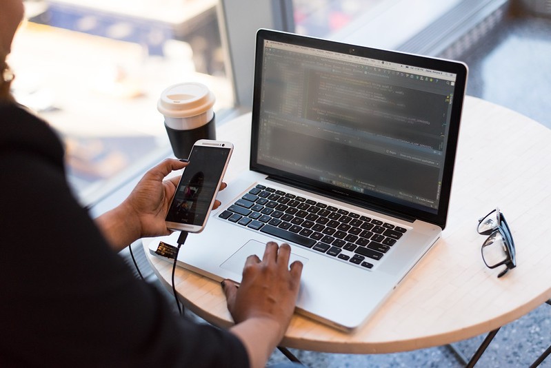 A person uses their mobile phone and their laptop at the same time