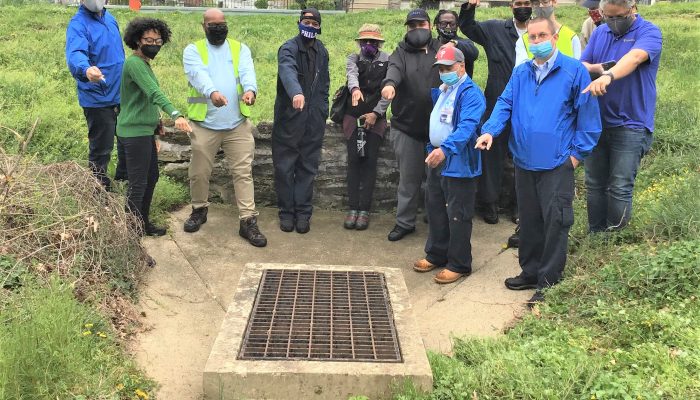 TCB Cleaning Ambassadors, PGA Instructors and Drew Brown from the Philadelphia Water Department pointing at a storm drain in Cliveden Park