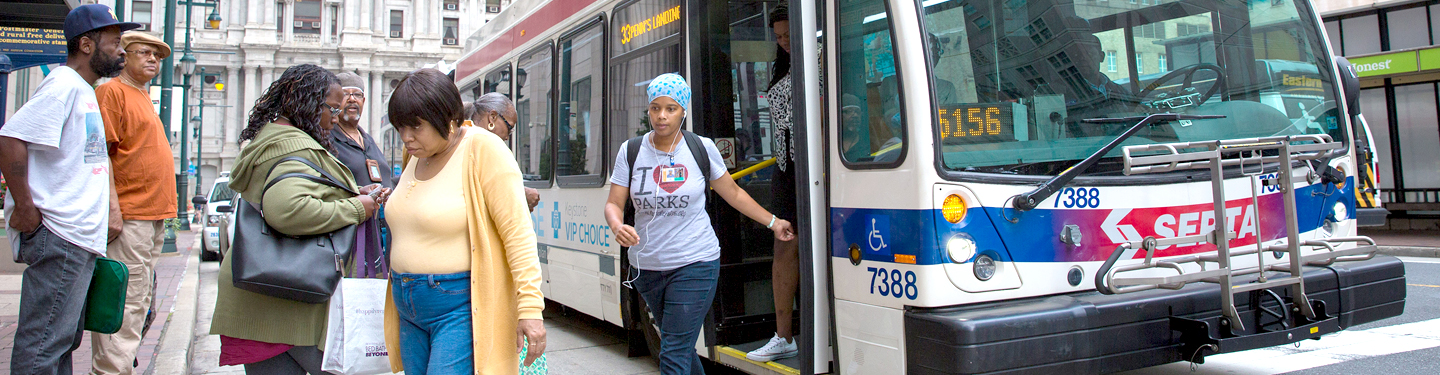 People stepping off of a bus near City Hall