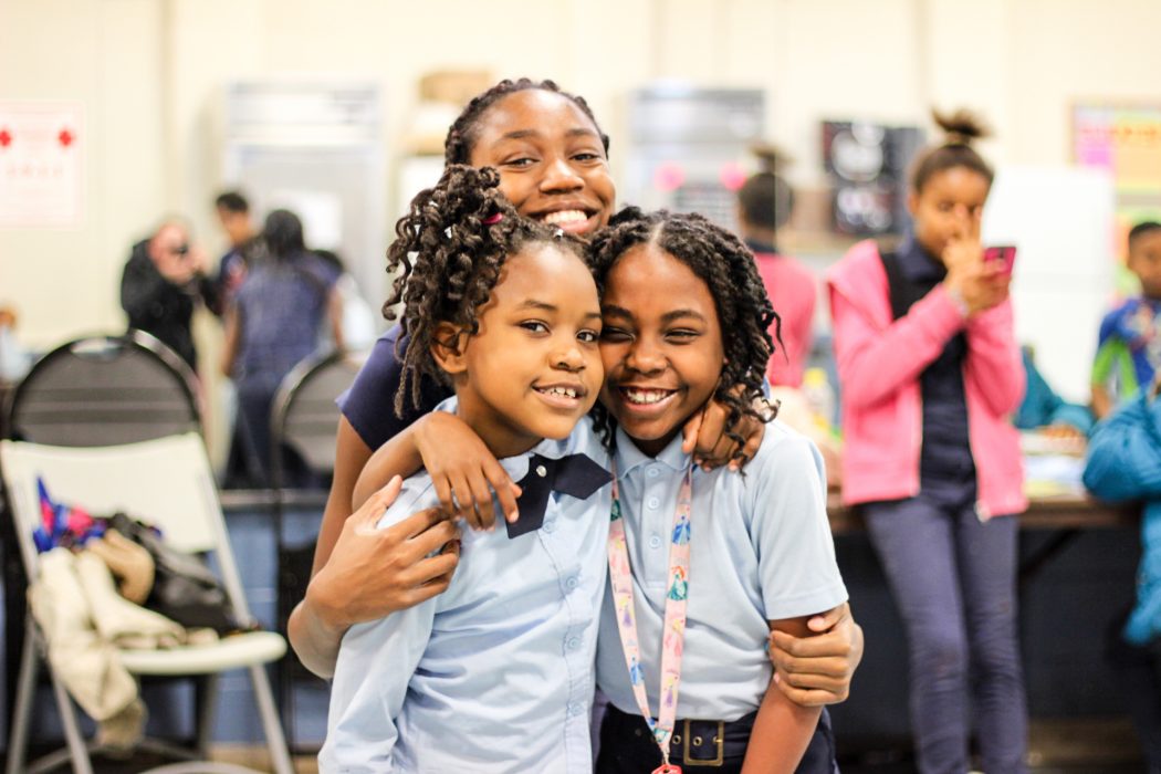 Students in an afterschool program, wearing matching school uniforms, smile for the camera