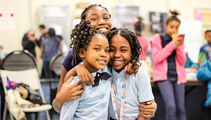 Students in an afterschool program, wearing matching school uniforms, smile for the camera