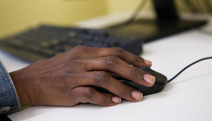 A close up of a hand on a corded mouse.