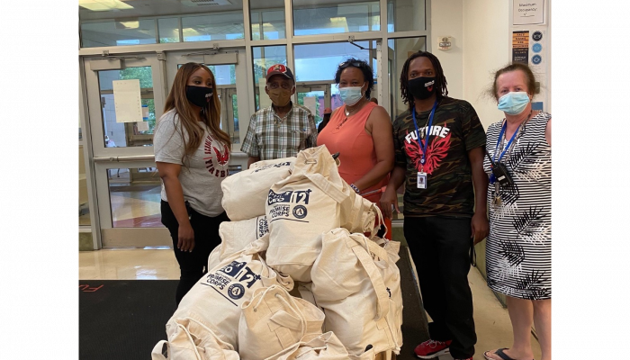 The principal and staff at High School of the Future accept gift bags for students.