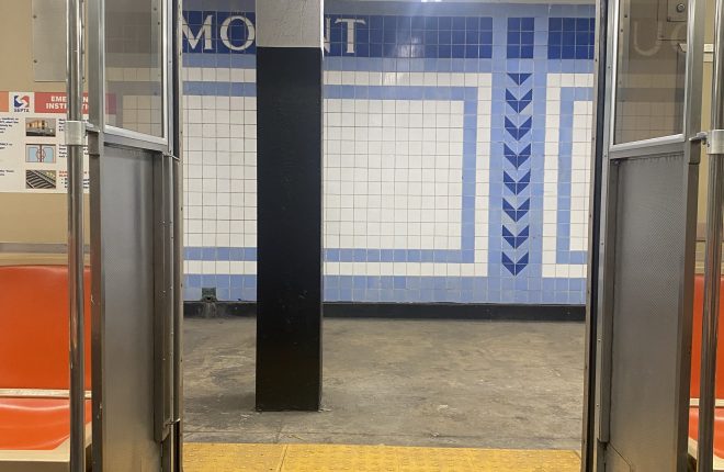 View from inside the subway, looking out through the open doors at a subway station.