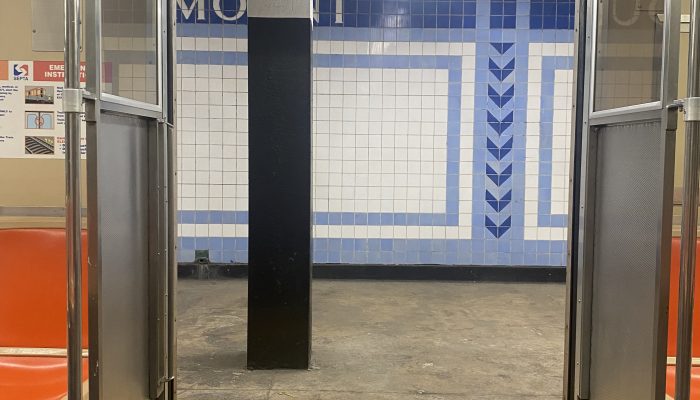 View from inside the subway, looking out through the open doors at a subway station.