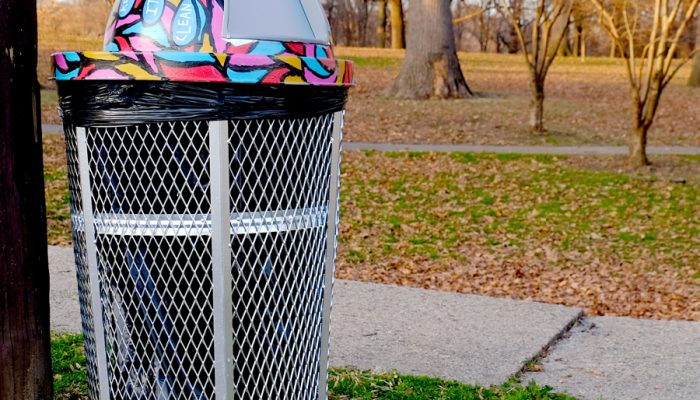 A trash can in front of a park