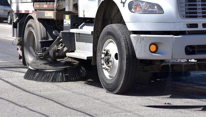 A lateral de um caminhão com uma vassoura de varrer a rua