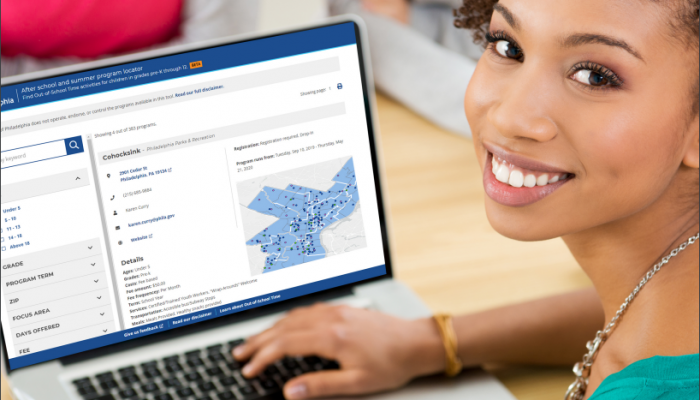 A woman smiles at the camera. Behind her, her laptop is open with the Program Locator on screen.