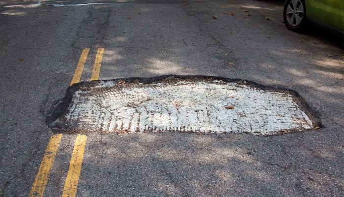 A large, rectangular hole in the driving lane of the street