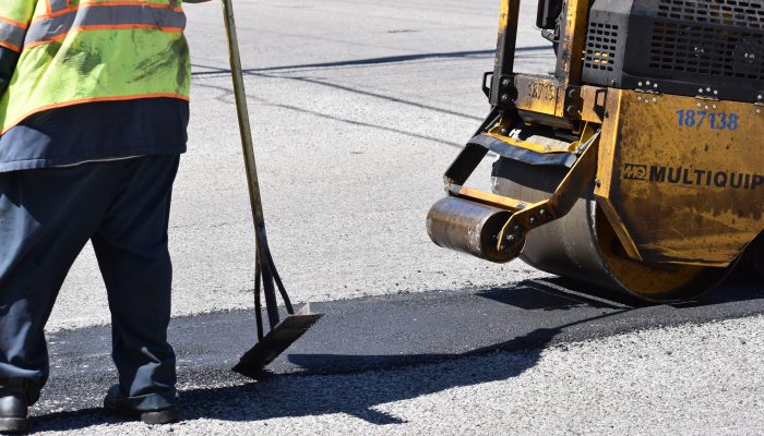 Alise el pavimento después de que una máquina haya alisado el bache con alquitrán nuevo