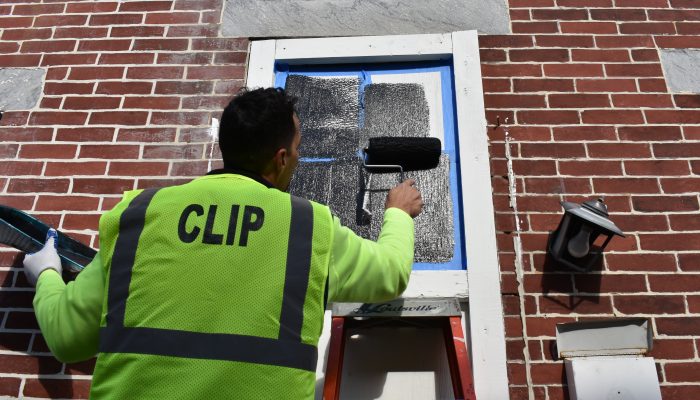 A worker from CLIP (Community life improvement program) is painting over graffiti on a wall