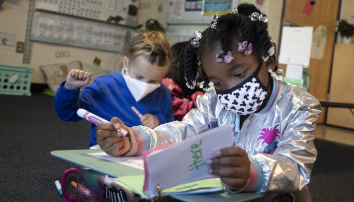 Masked children reading in class