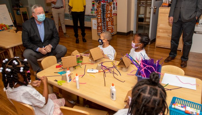 PHLpreK children sit at a table creating crafts with Mayor Kenney sitting near by.