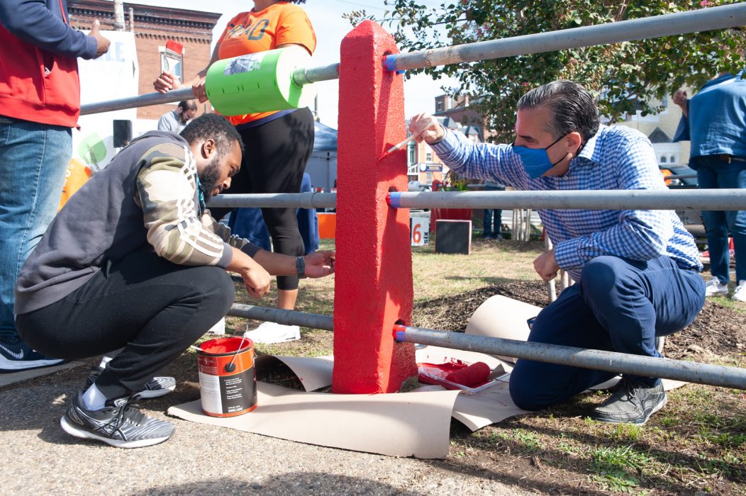 two people paint a fence