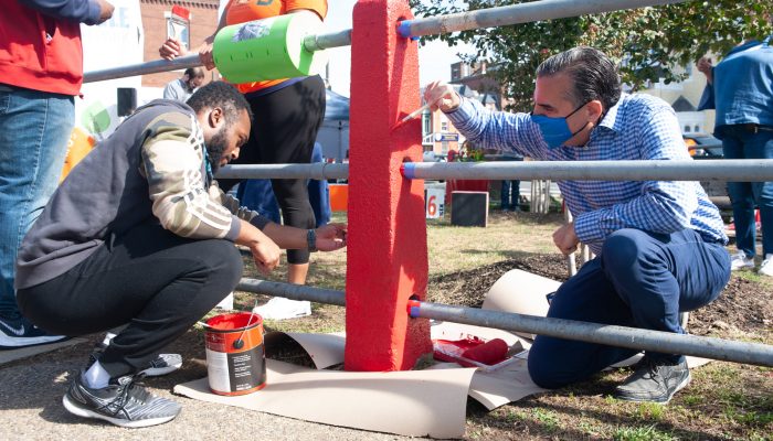 two people paint a fence