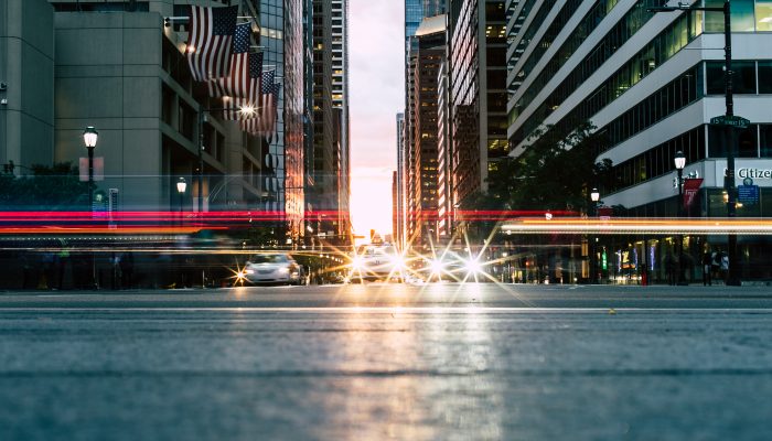 Close-up of a Philadelphia street. Headlights of cars in the background along with Philadelphia buildings.