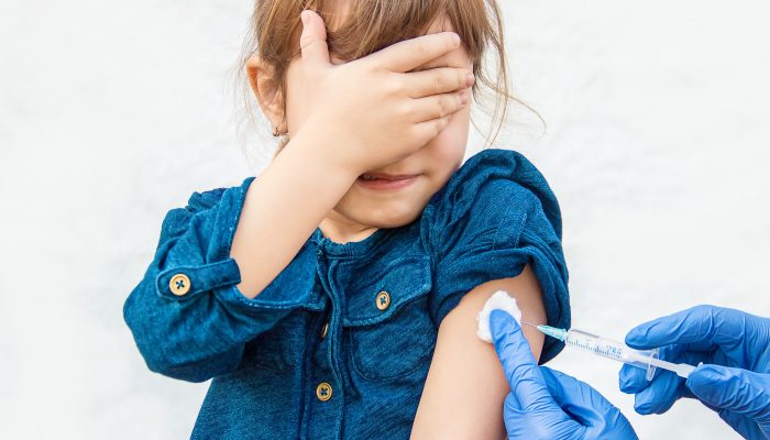 Child covering her eyes as she receives a vaccine