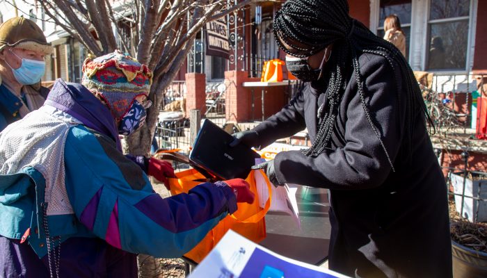 A woman is putting a laptop in an older woman's bag at an outdoor distribution event. All laptops given out at this event were distributed and refurbished through PHLDonateTech.