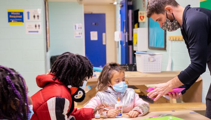 a teacher helping students with an arts and crafts project