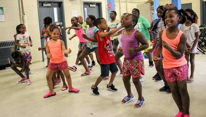 A room full of kids dancing at summer camp.