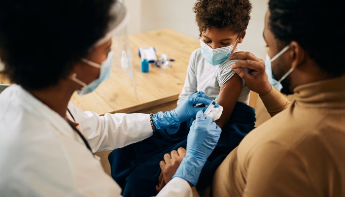 Niño afroamericano cuyos padres reciben la vacuna